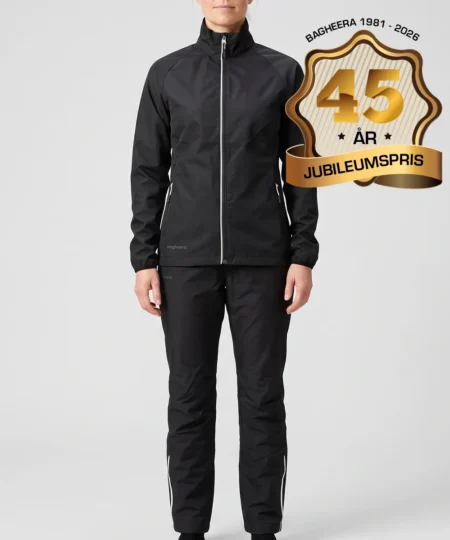 Kvinlig modell visar Selva svart jacka och svarta byxor i ett paketpris. Modellen står framifrån i en studio med ljusgrå bakgrund.